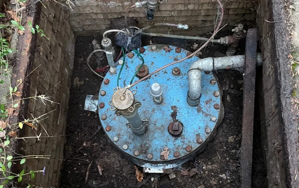 Domschacht eines unterirdischen Heizöltanks im Garten mit blauem Deckel